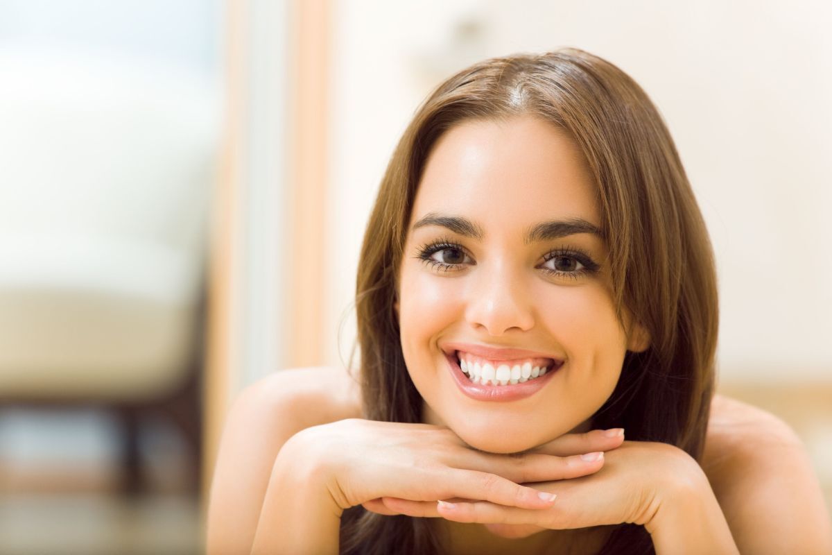 Smiling woman with straight white teeth demonstrating results from cosmetic dental treatments.