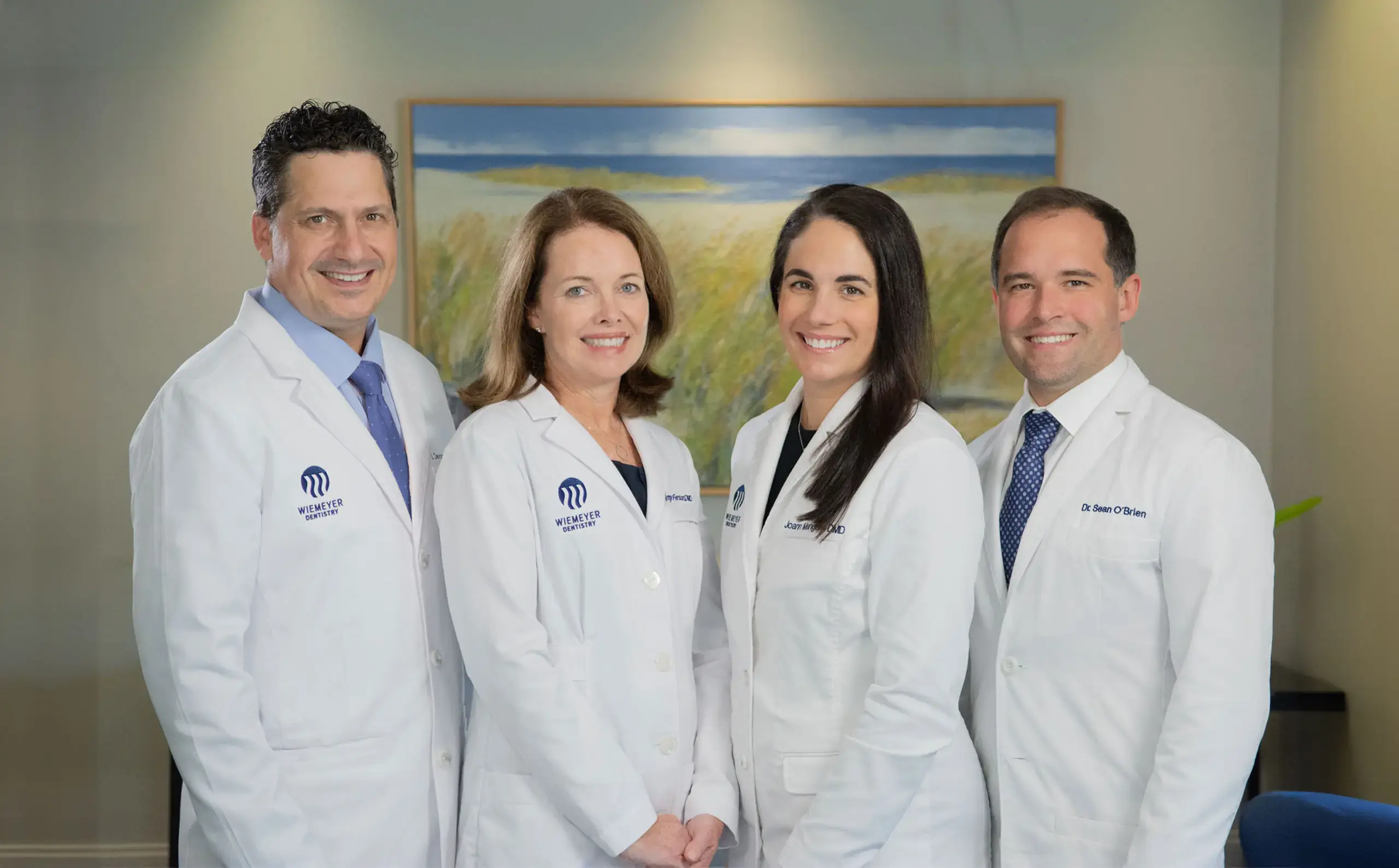 img-drs-home-new Four dental professionals in white coats smiling at Wiemeter Dentistry in Duxbury, MA.