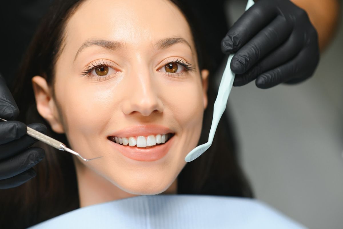 Patient smiling during cosmetic dental examination with dentist using dental mirror in Duxbury office.