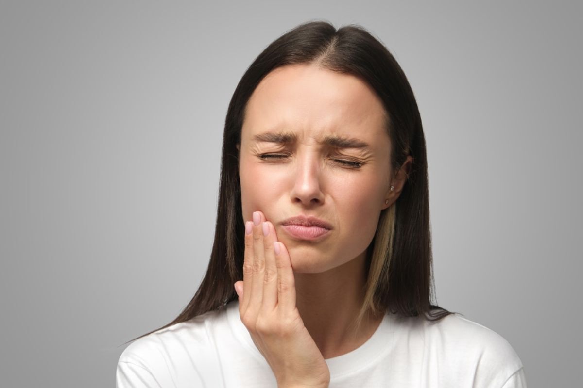 TMJ Treatment Duxbury Woman with jaw pain holding her cheek, illustrating TMJ symptoms and dental health concerns.