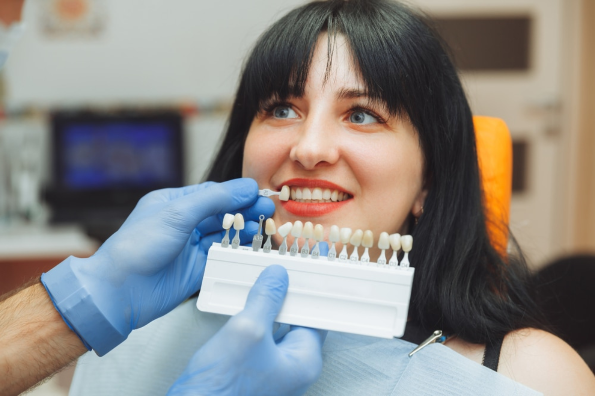 Dentist showing patient dental veneer shade guide to match natural tooth color and face shape.