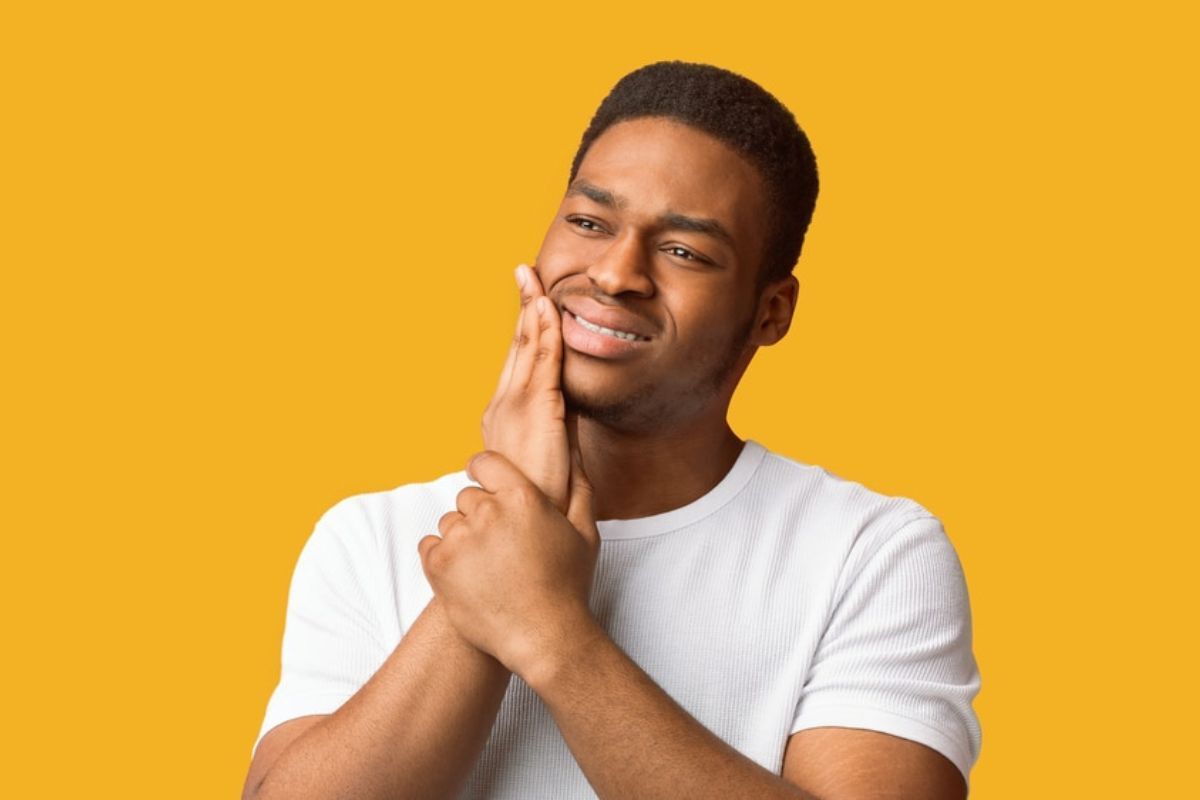 TMJ Treatment Duxbury Man holding his cheek in pain, possibly experiencing TMJ symptoms or dental discomfort.