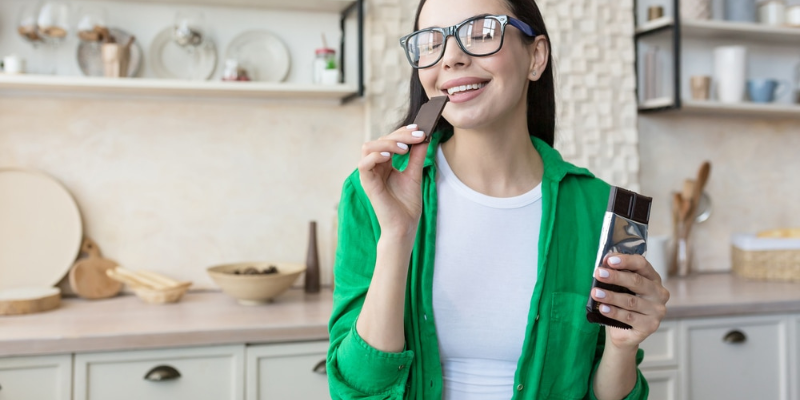 World Chocolate Day with a Smile Woman holding paintbrush in green shirt smiling in kitchen for World Chocolate Day dental celebration.