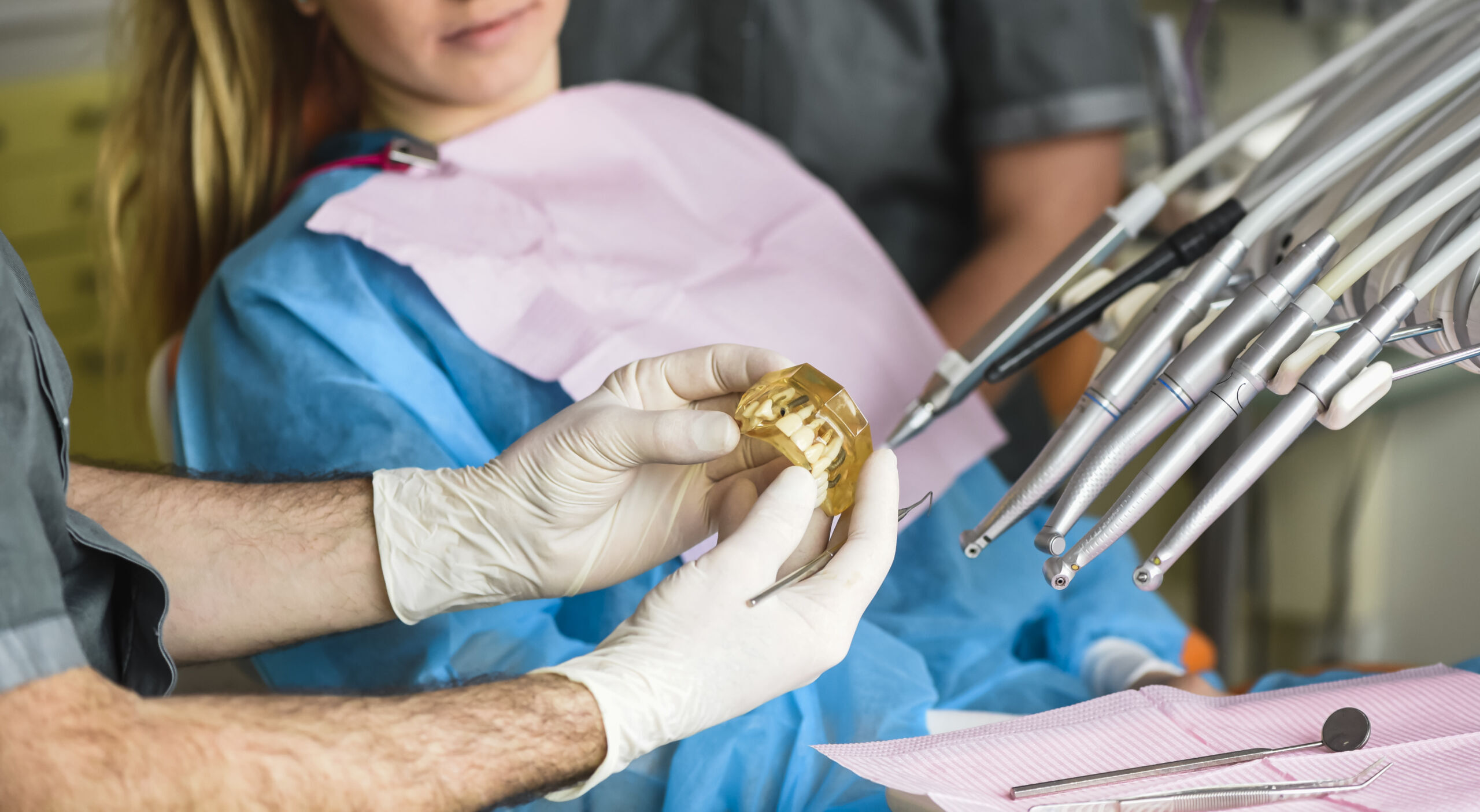 dentist Dentist displaying a gold dental implant crown to patient during bone grafting consultation in Duxbury.