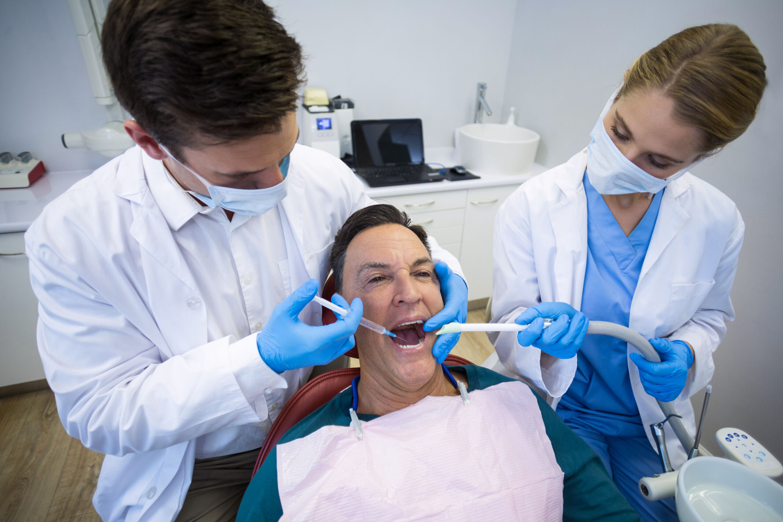 Two dentists examine a patient's teeth during a restorative dental treatment in Duxbury.