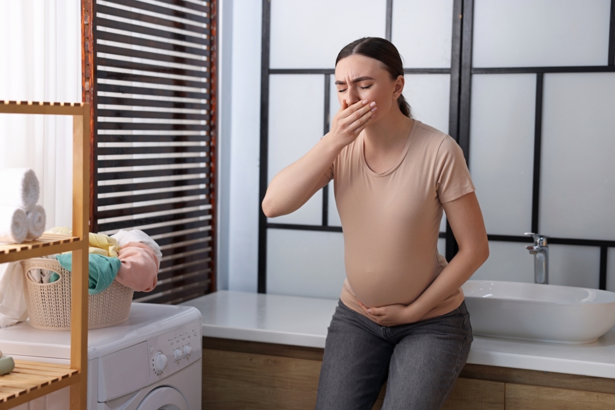 TMJ Pain During Pregnancy Pregnant woman experiencing TMJ pain and nausea in bathroom at home.