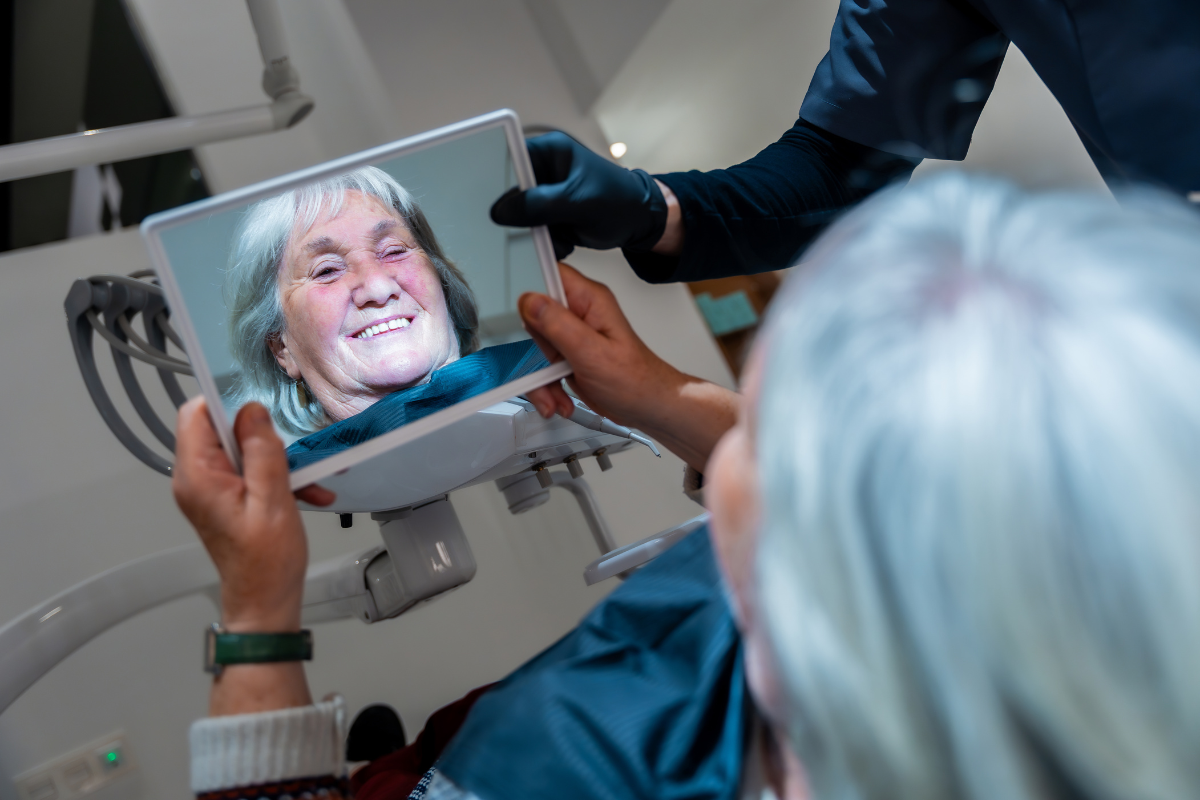 Senior patient viewing her digital smile design on intraoral monitor during dental consultation.