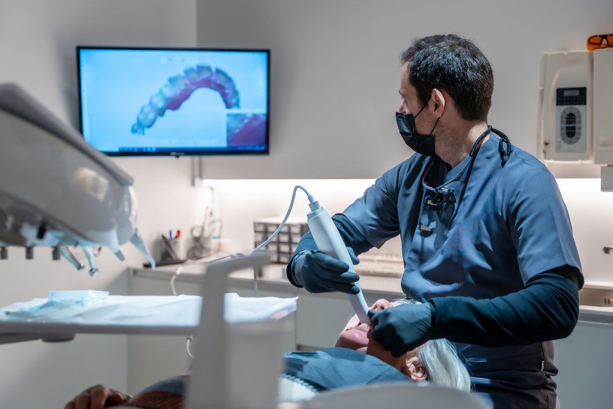 The Importance of Personalized Treatment Plans in Modern Dentistry Dentist holding intraoral scanner while viewing 3D tooth scan on monitor during patient examination.