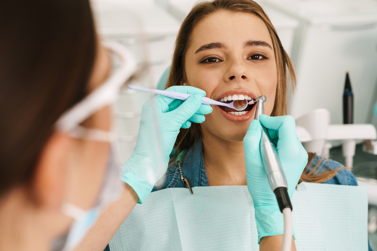 Dentist examining patient's teeth during dental checkup in office.