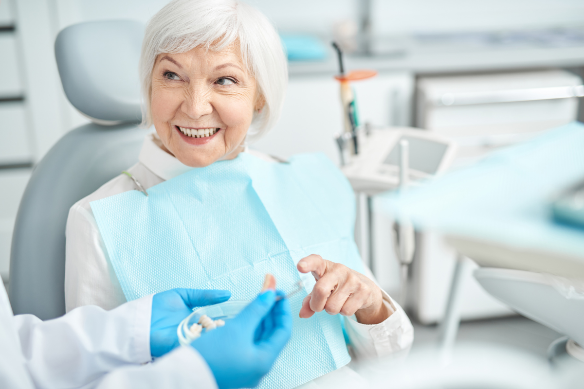 Dental Implants for Young Adults_ When Is the Right Age Senior woman smiling in dental chair wearing protective bib during appointment.