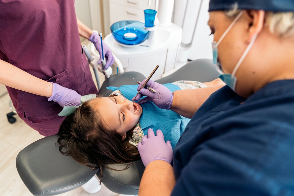 Young patient receiving dental examination from dentist and assistant in Duxbury office.