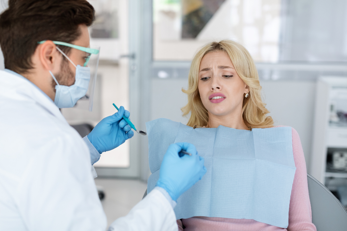 Dentist discussing treatment options with anxious patient in modern dental office.