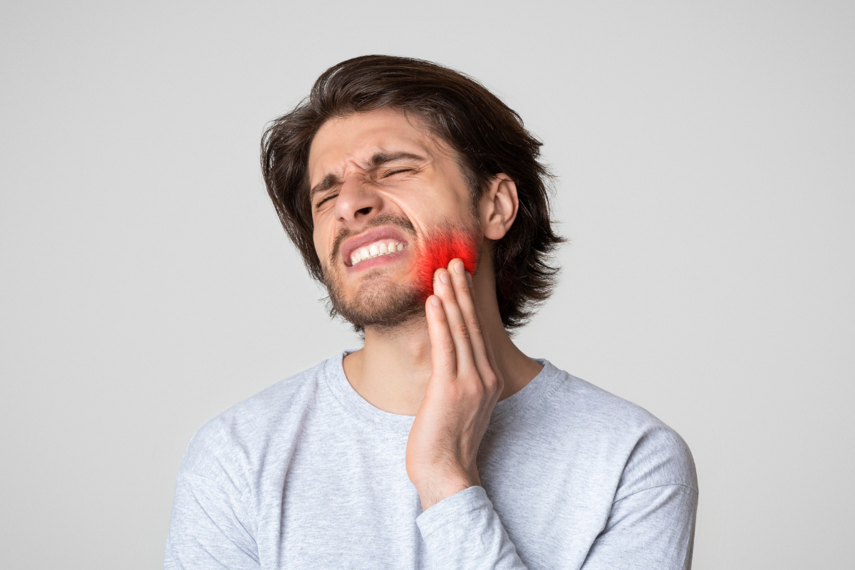 Man holding his jaw experiencing pain, illustrating one-sided jaw discomfort.